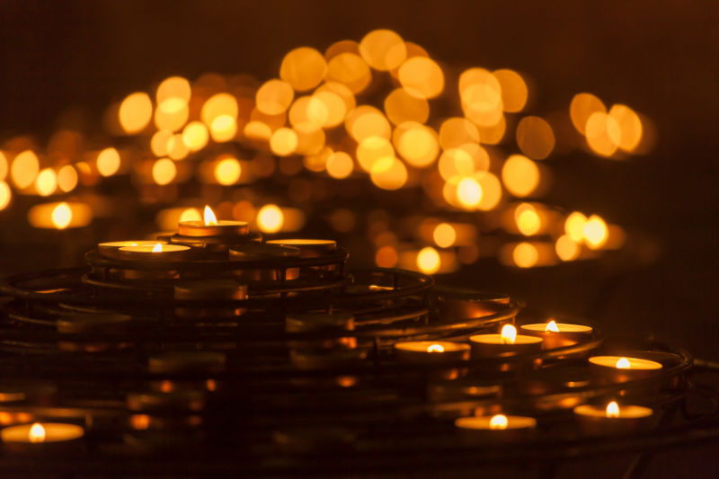 Dozens of
			candles flickering with warm orange light.